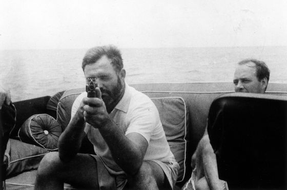 船の上で銃をかまえるヘミングウェイの白黒写真